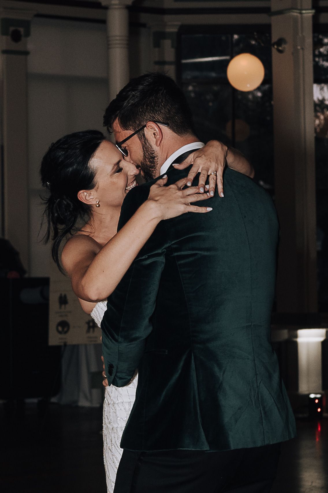 Couple sharing romantic first dance moment at dimly lit wedding reception.