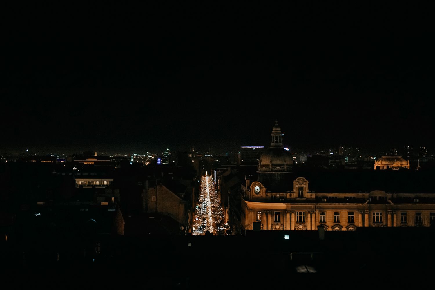 Nighttime cityscape with illuminated Christmas lights and historic buildings.