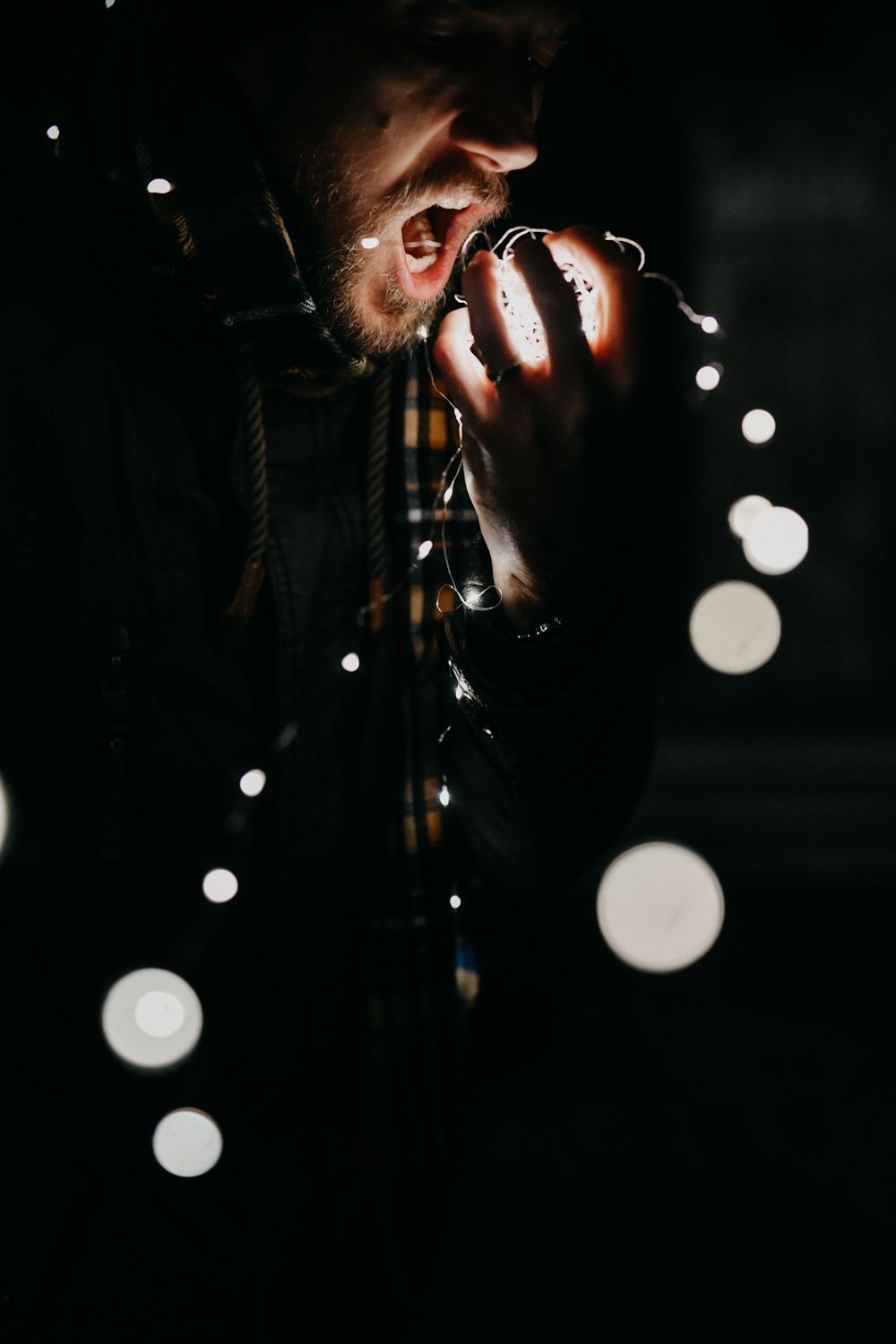 Dark atmospheric photo of someone taking pictures with glowing bokeh lights in the background.