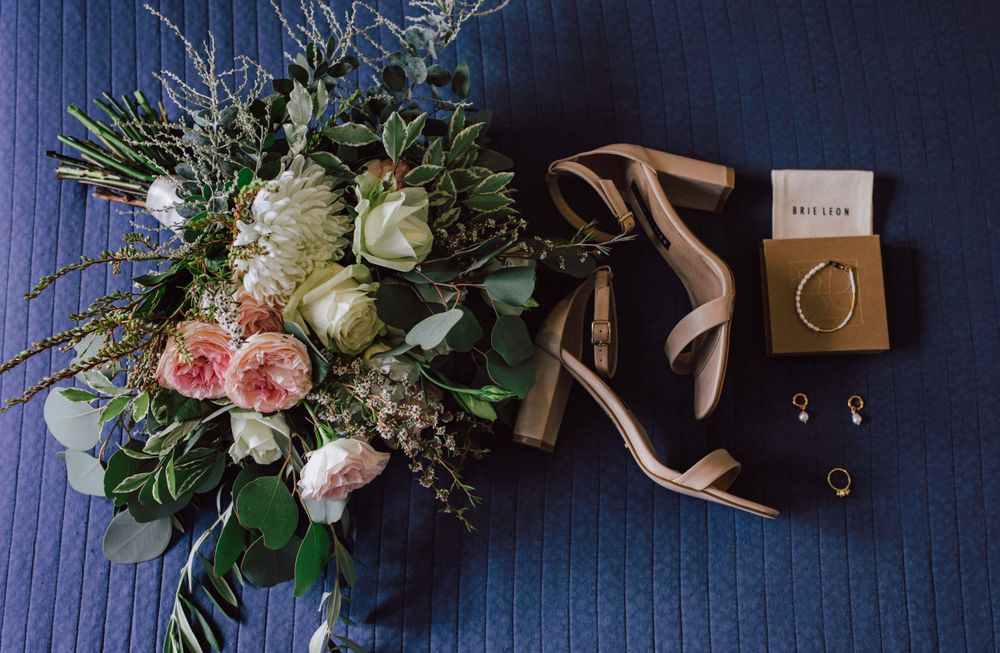 Flatlay of bride's shoes bouquet and earrings at her wedding
