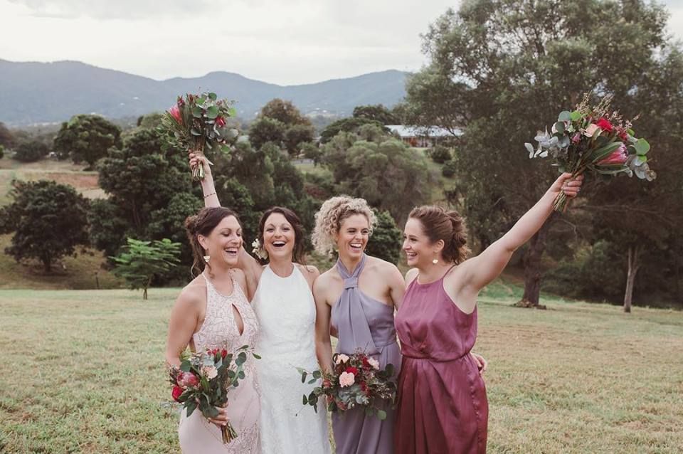 Bride and her bridesmaids holding their bouquets in the air