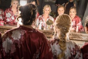Reflection of bridal party getting ready at mirror-lined vanity with warm lighting.