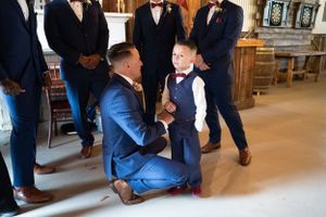 A touching moment between a man in blue suit and young boy in formal attire inside a church.