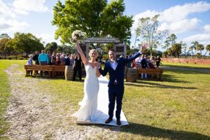 Celebratory moment during outdoor wedding ceremony with rustic bench seating and natural backdrop.