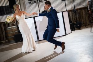 Dynamic dance move captured during wedding celebration in rustic indoor venue.