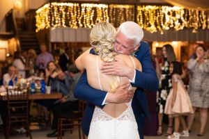 A romantic dance between a couple surrounded by string lights at a wedding reception.