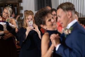 Wedding guests capture photos on phones during a special dance moment.