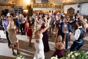 Wedding guests dance together in a decorated reception venue.