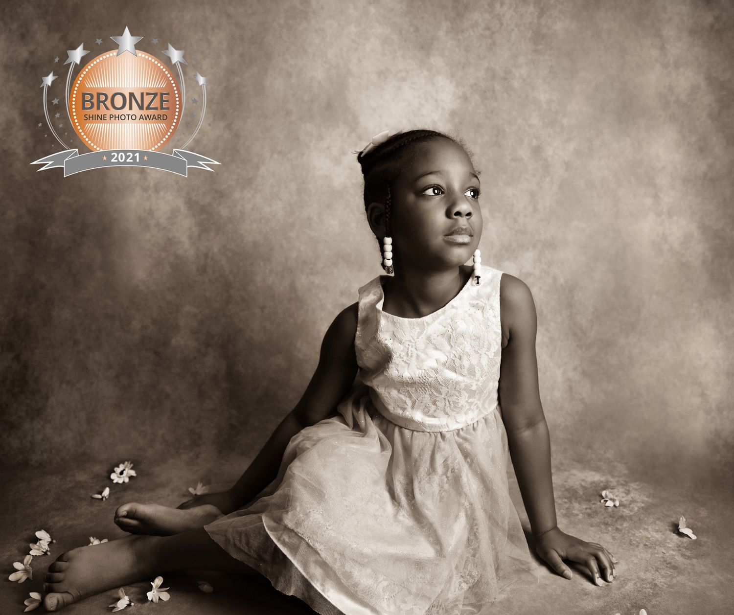 Fine art portrait in sepia tones featuring a lace dress against a textured backdrop.