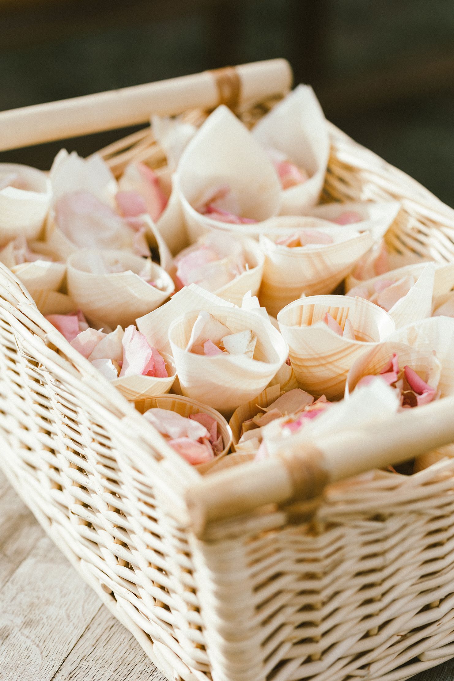 White woven basket filled with delicate pink rose petals.