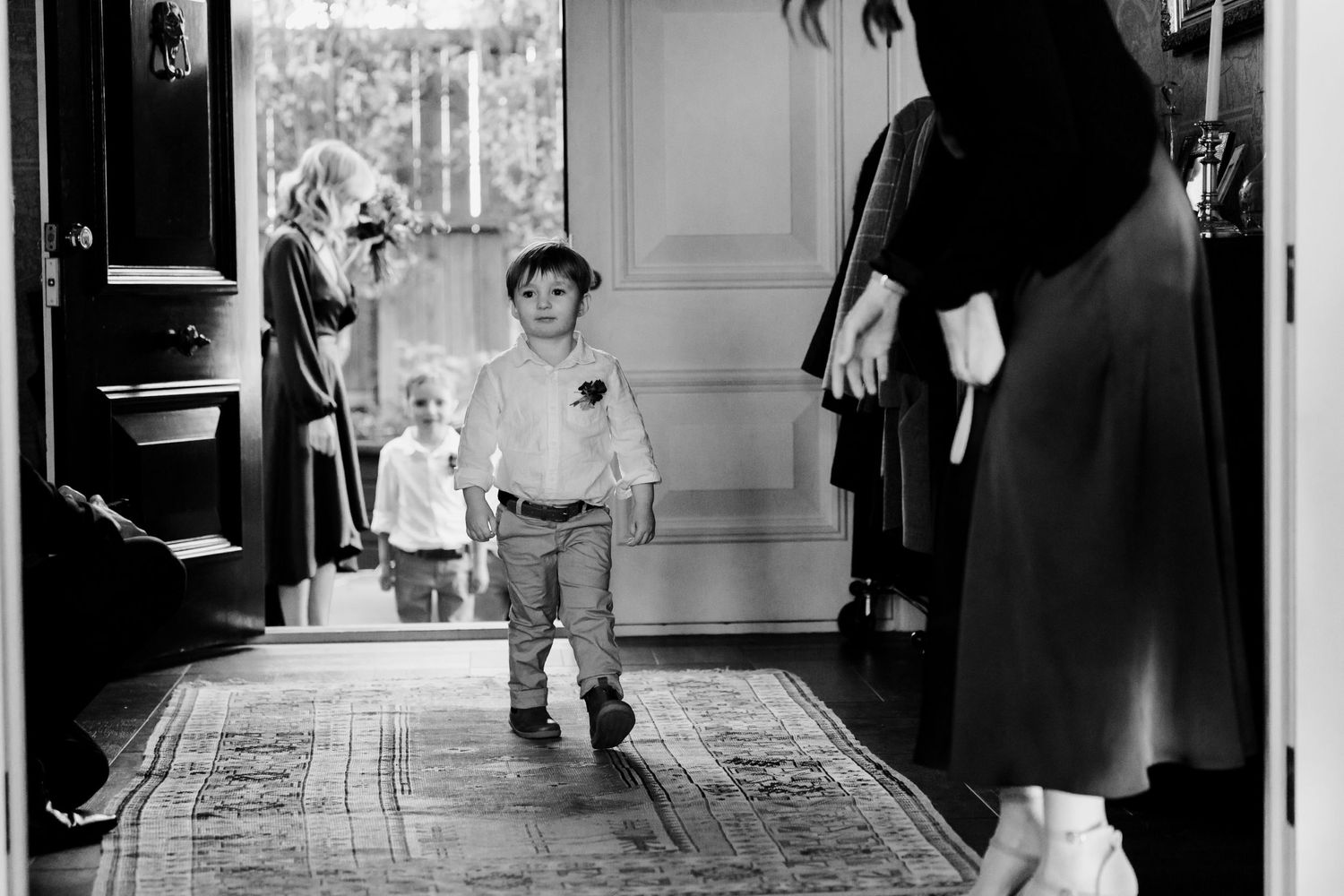 Black and white photo of a child walking through a doorway.