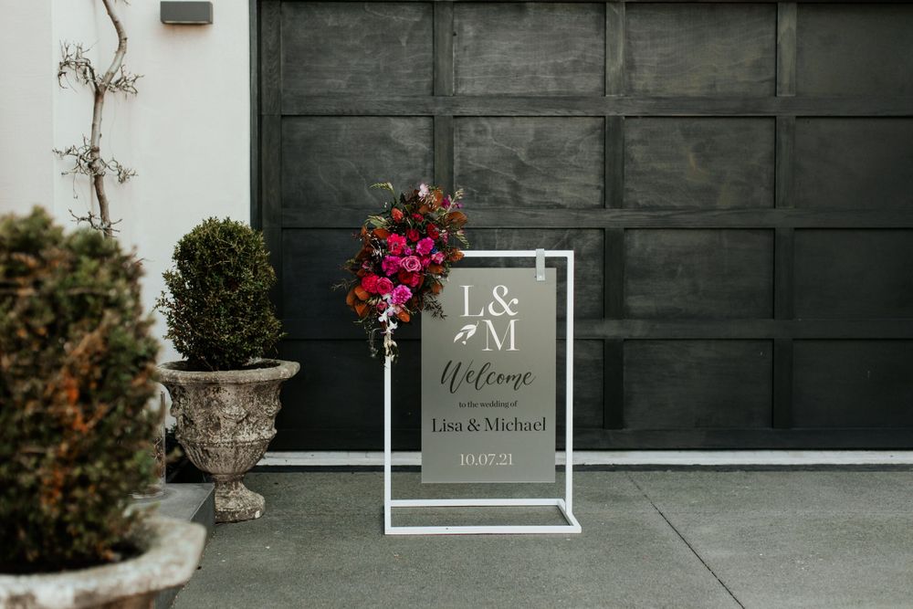 Modern welcome sign with floral accent displayed against dark garage door.
