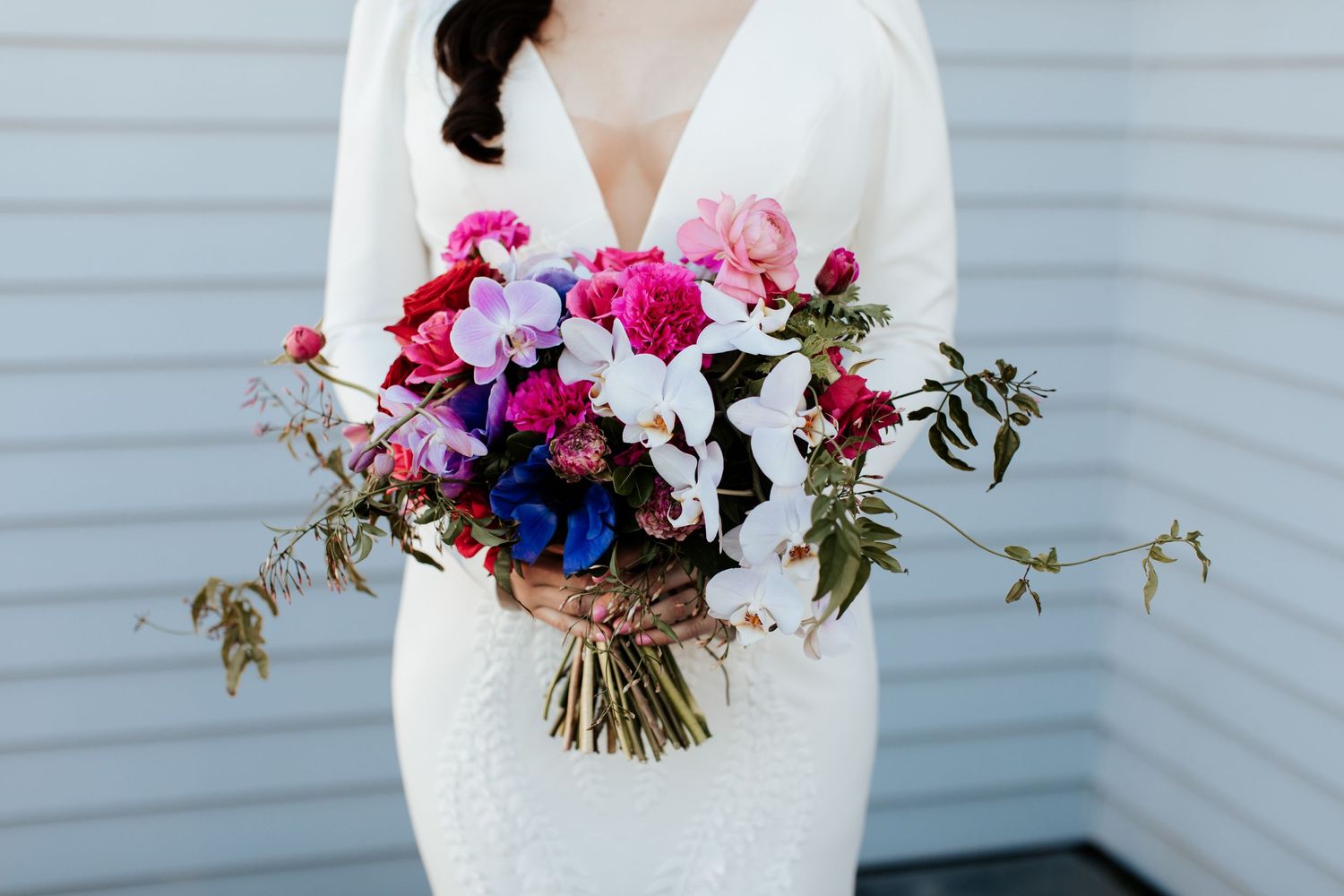 Close-up of vibrant pink, purple and white wedding bouquet with cascading greenery.