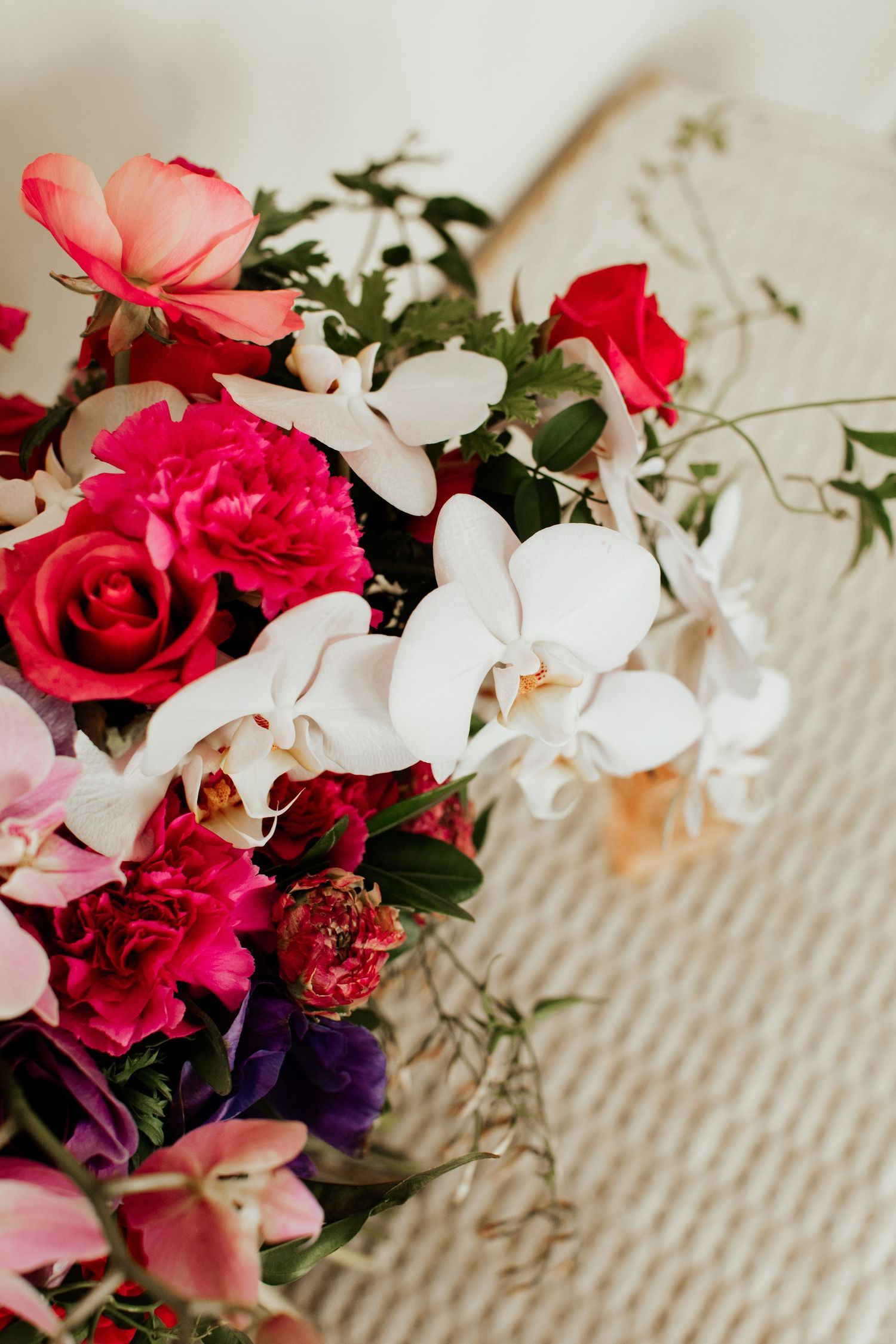 Close-up of romantic wedding bouquet with red roses, white orchids and pink flowers.