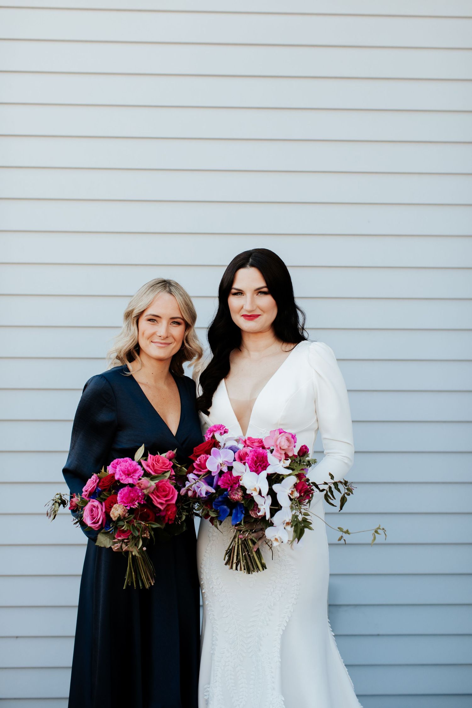 Wedding party poses in contrasting white and navy dresses with matching pink and purple bouquets.