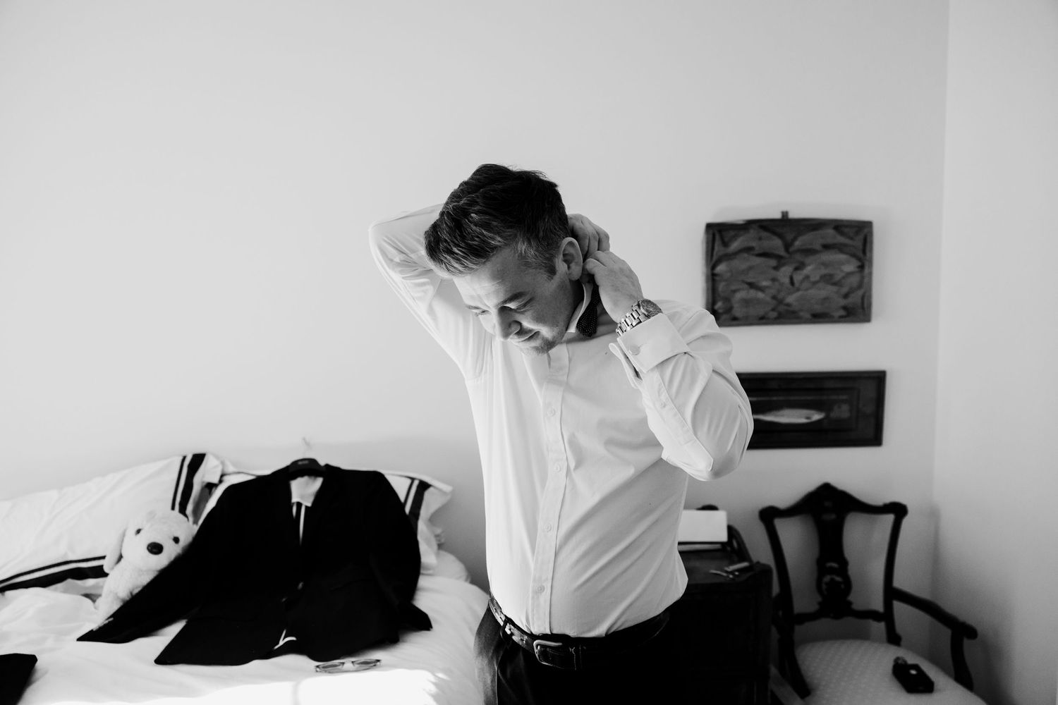 Person in white shirt getting dressed in formal attire.