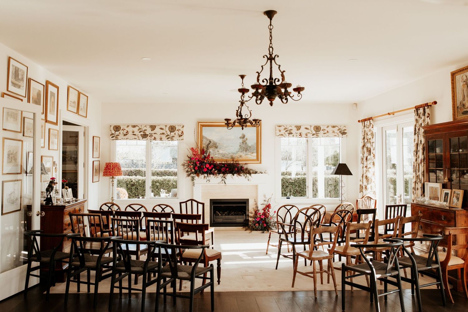 Vintage-style reception room with chandelier and wooden chairs arranged for wedding ceremony.