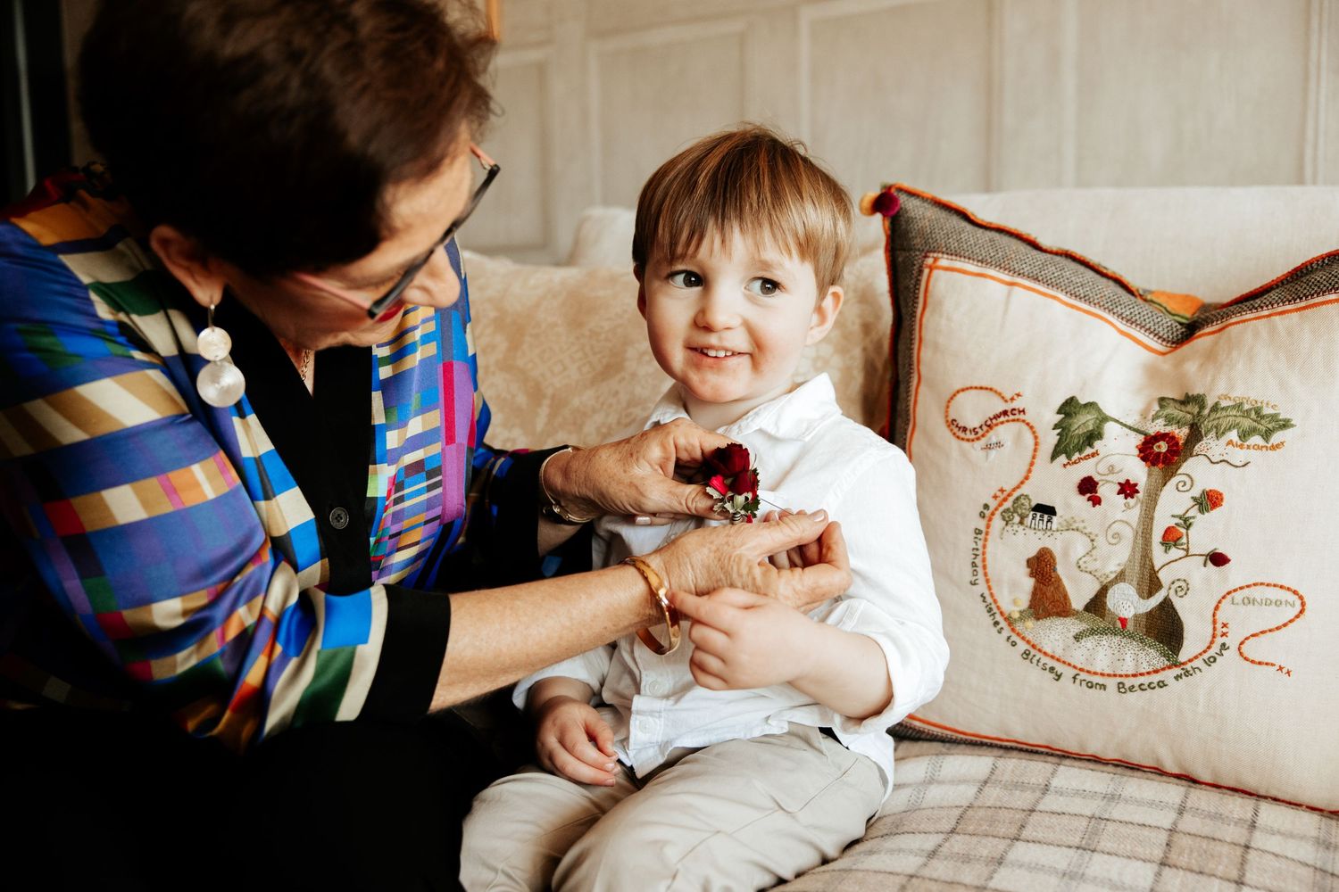Candid moment between adult and child sitting on couch with decorative pillow.