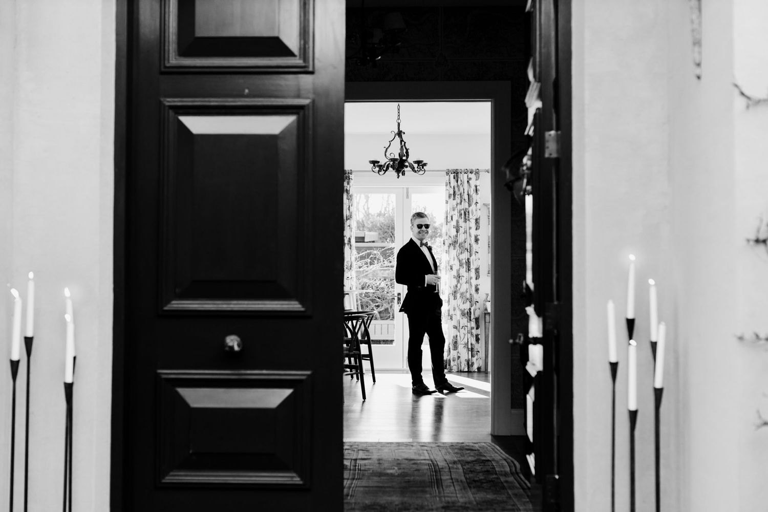 Black and white photo of a silhouetted figure framed by doorways and candles.