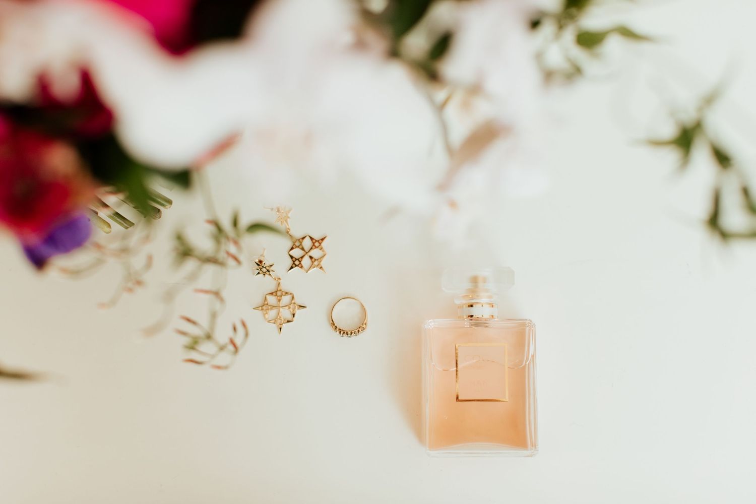 A perfume bottle floating elegantly among delicate floral elements and jewelry pieces.