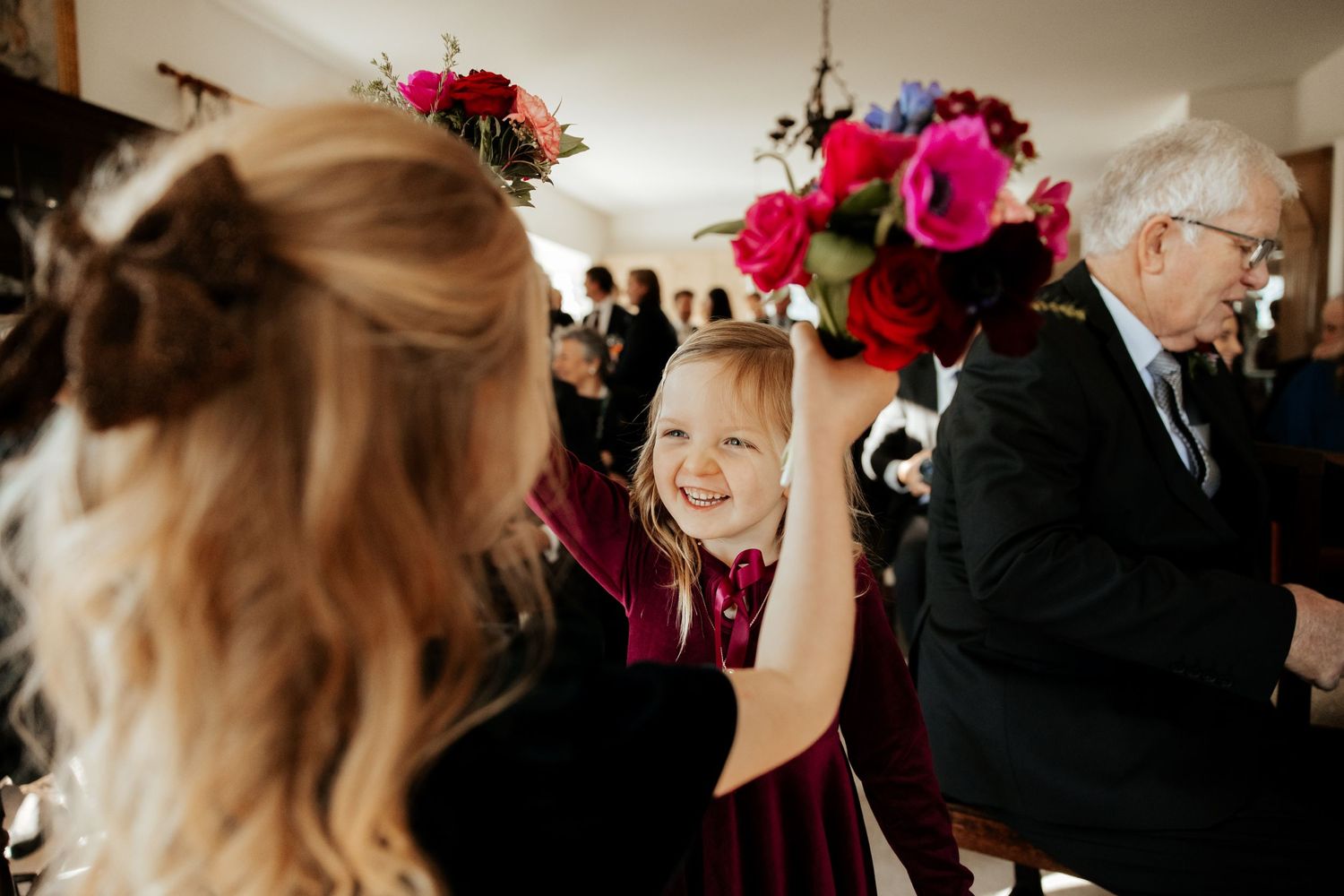 Wedding celebration scene with vibrant pink floral arrangements and joyful guests.