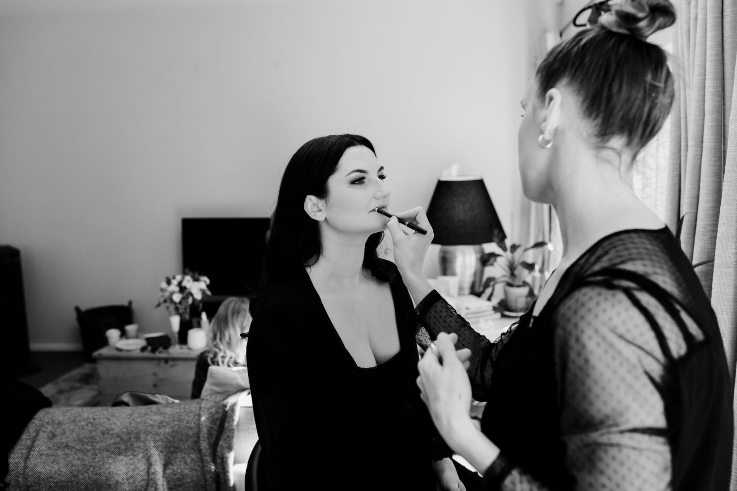 Professional makeup artist applying cosmetics in black and white photography.