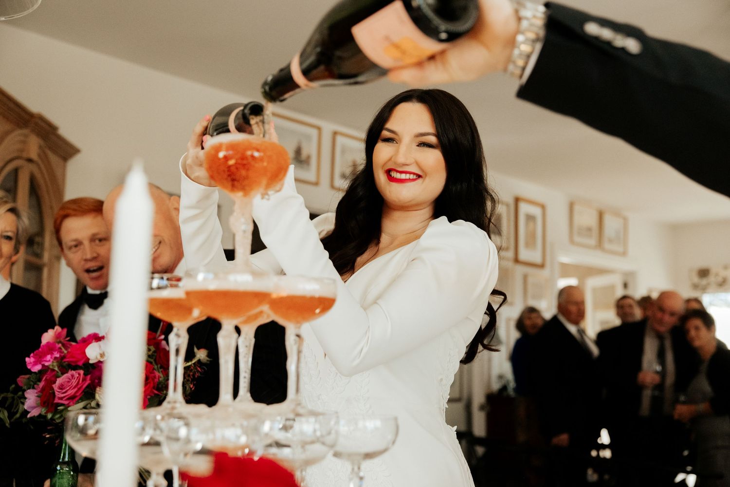 Champagne being poured into an elegant tower of glasses during a wedding celebration.