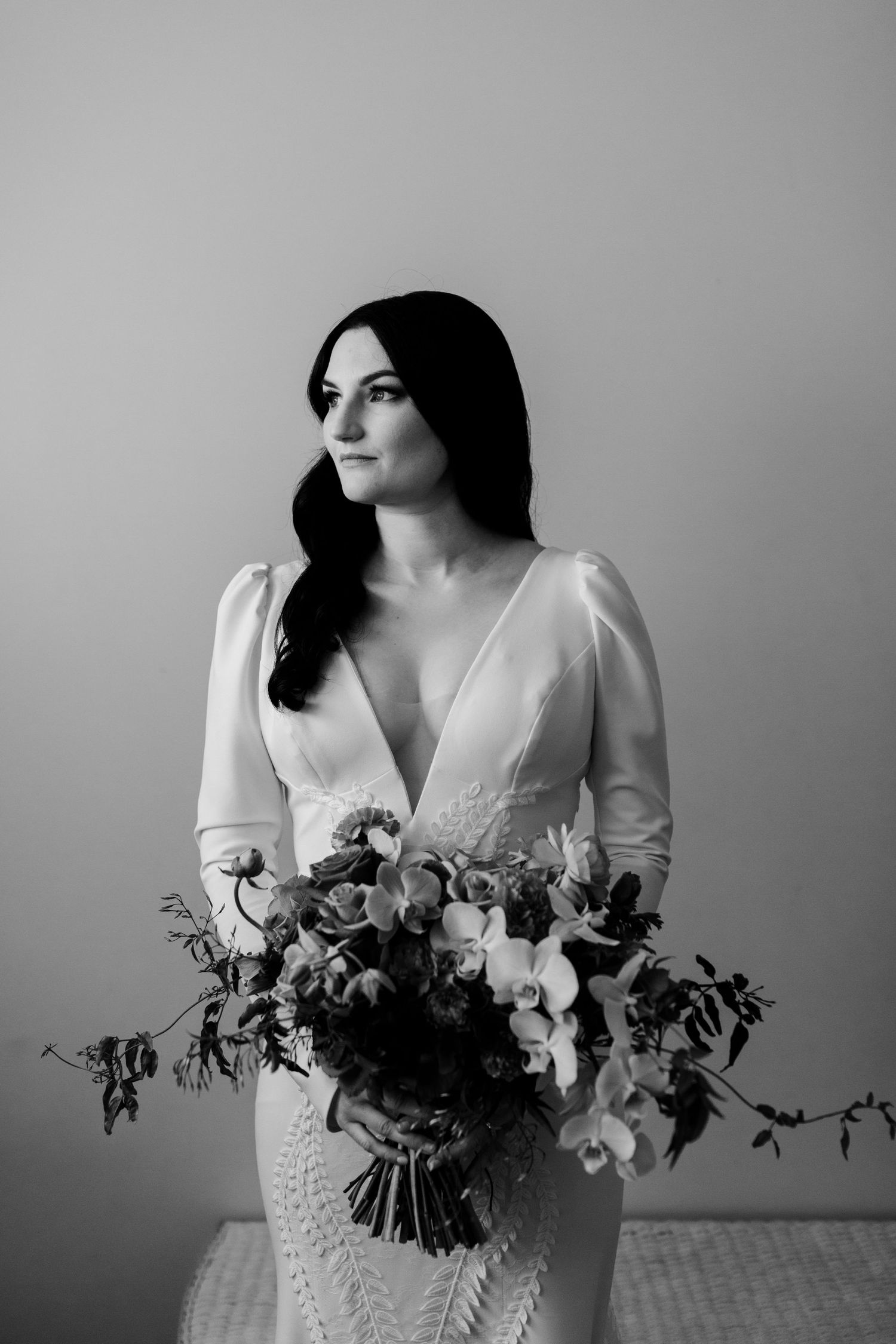 Black and white bridal portrait featuring elegant long-sleeve wedding dress and cascading bouquet.