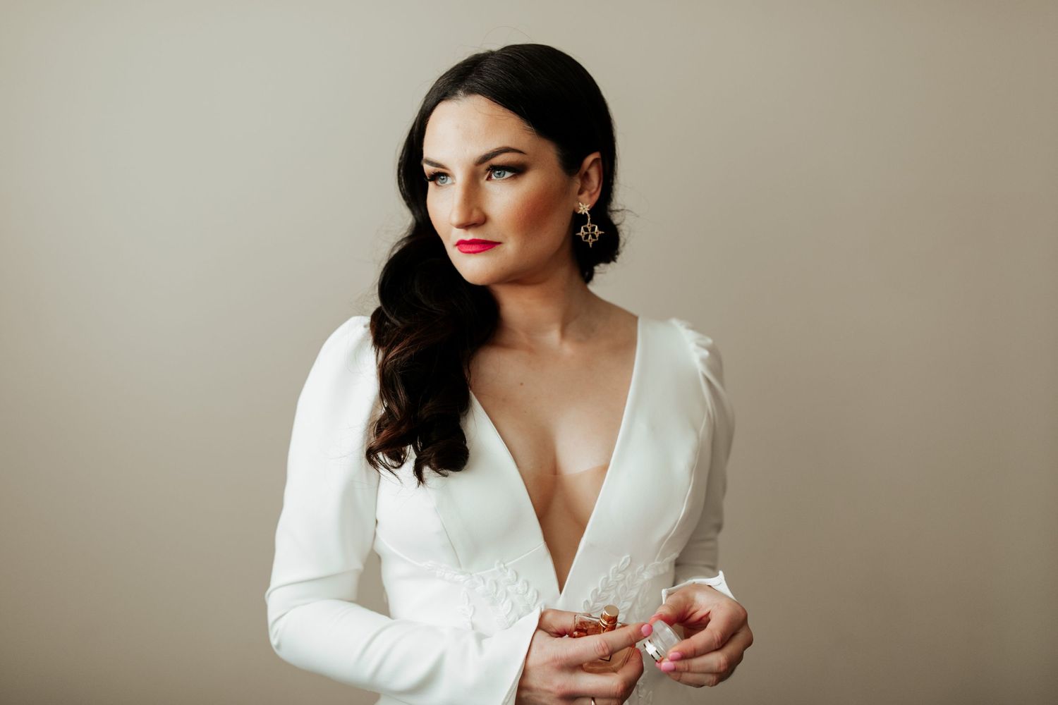 Elegant white long-sleeve wedding dress with plunging neckline in studio setting.