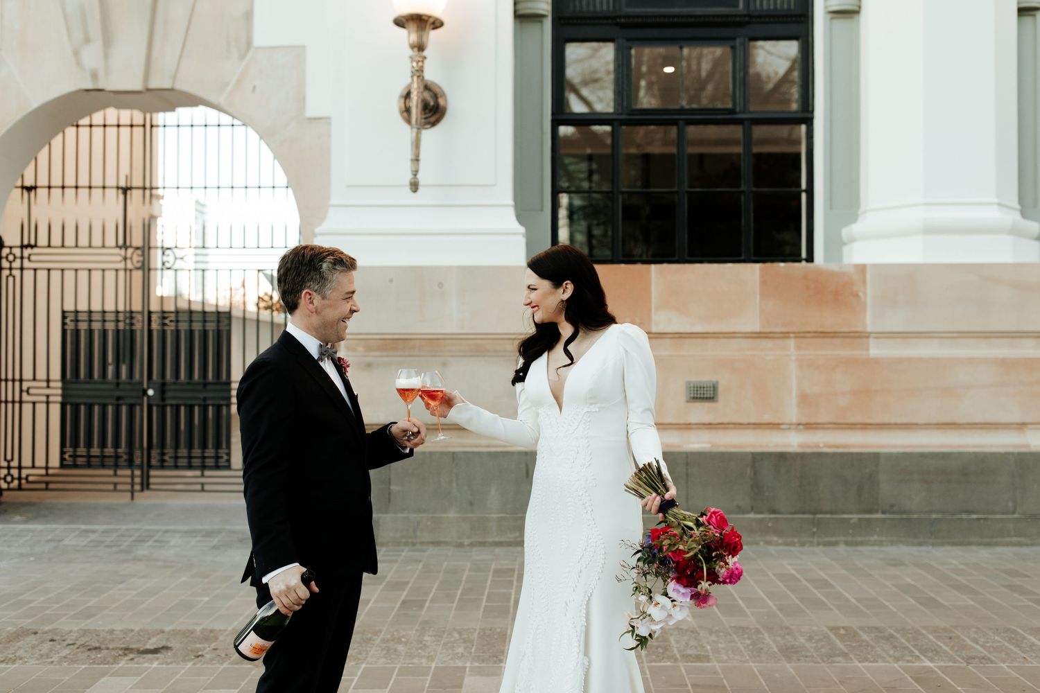 Candid moment between couple during wedding ceremony against classical architecture.