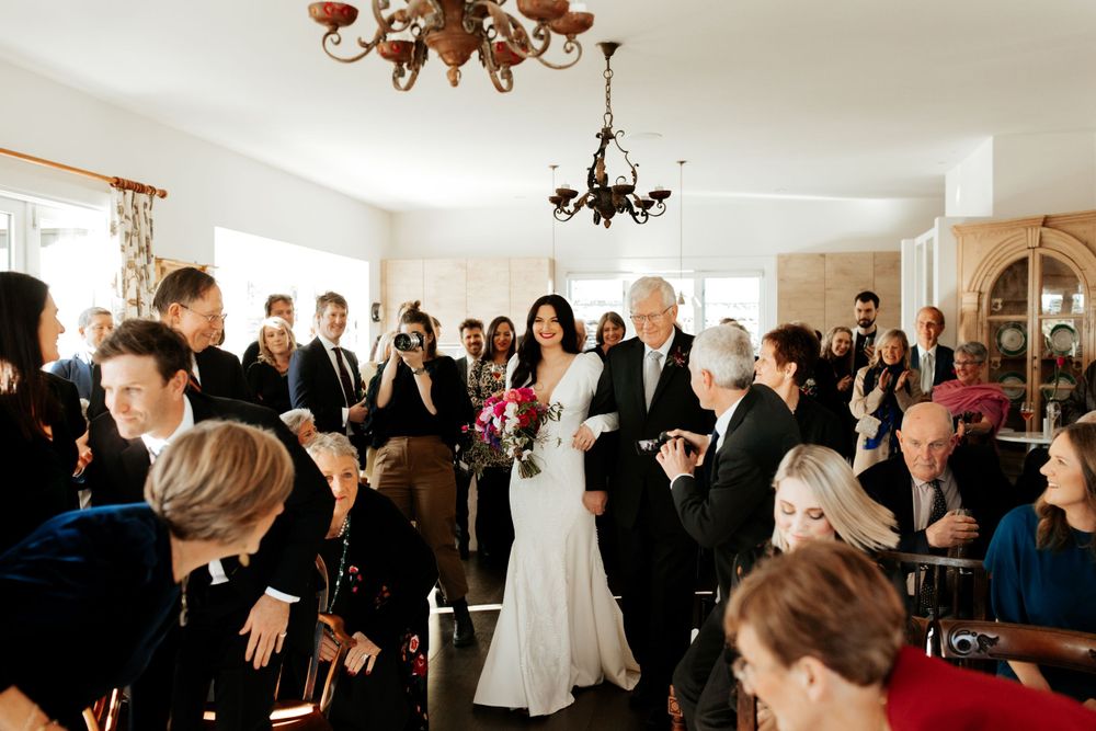 Indoor wedding ceremony with guests gathered in an elegant room.
