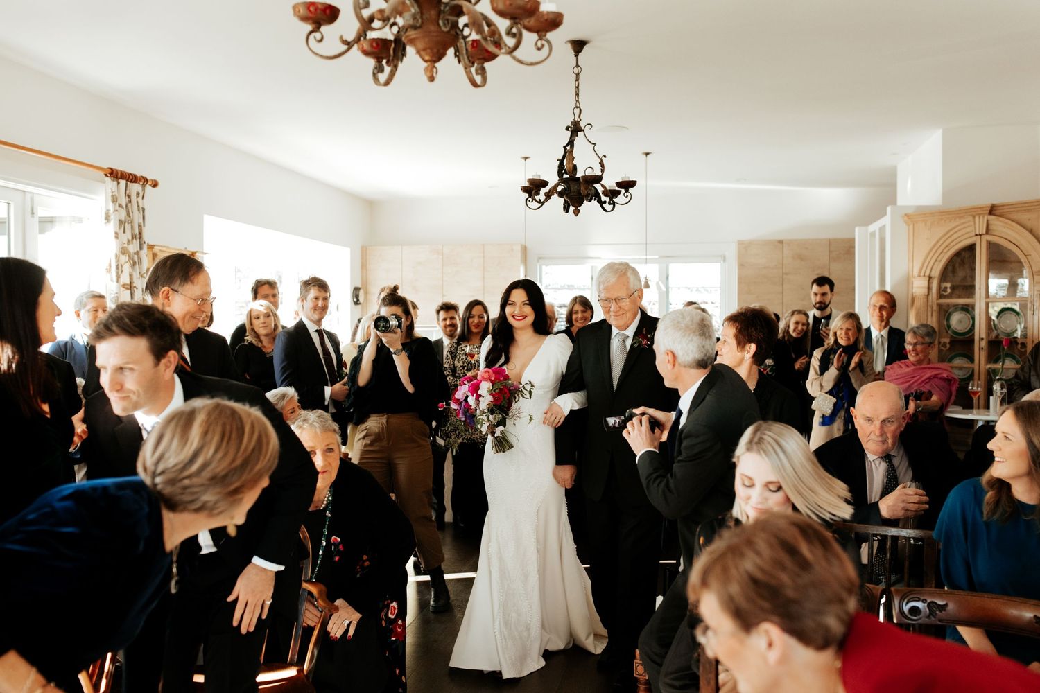 Indoor wedding ceremony with guests gathered in an elegant room.