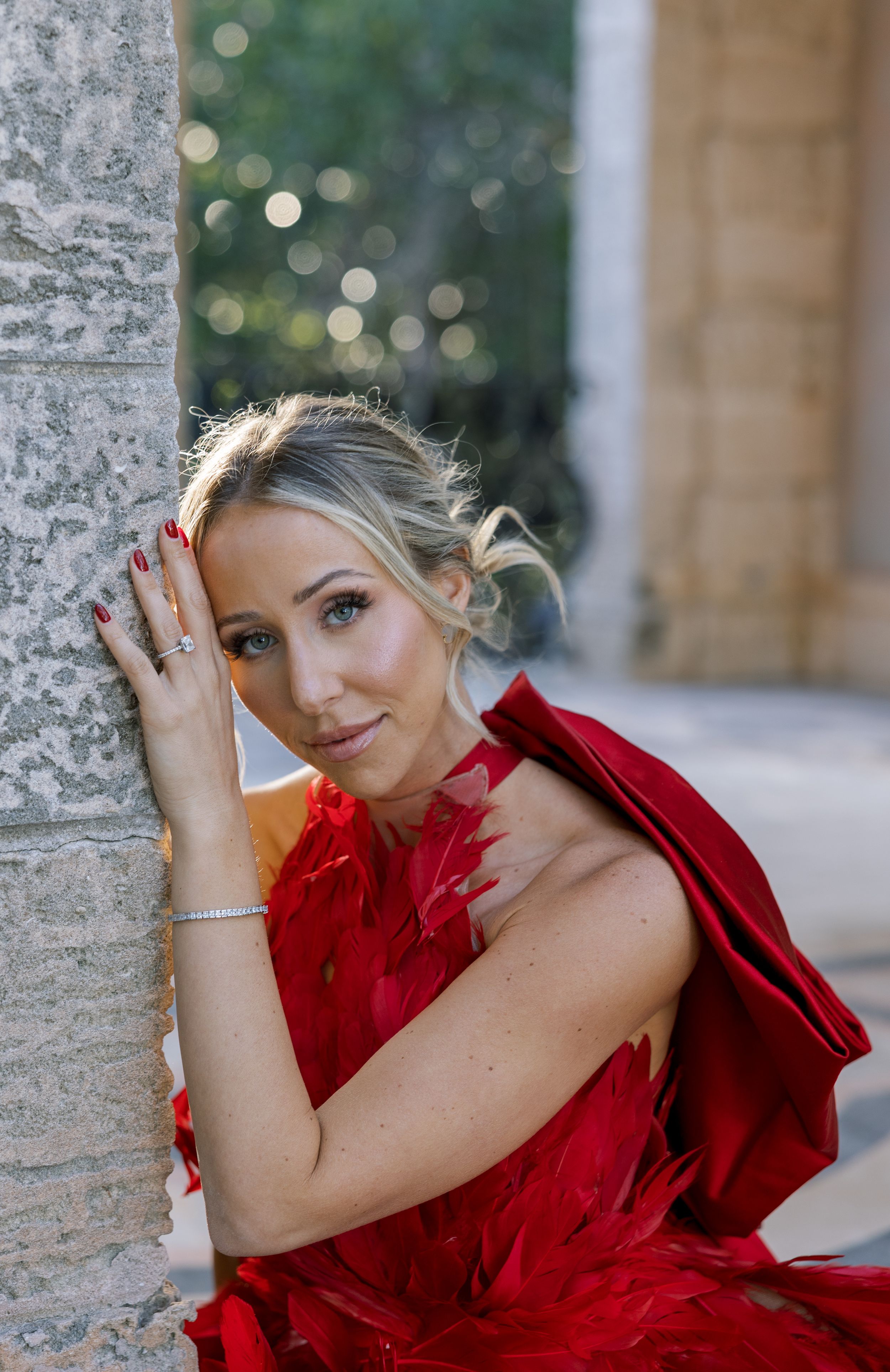 Portrait shot against stone columns with soft bokeh background.