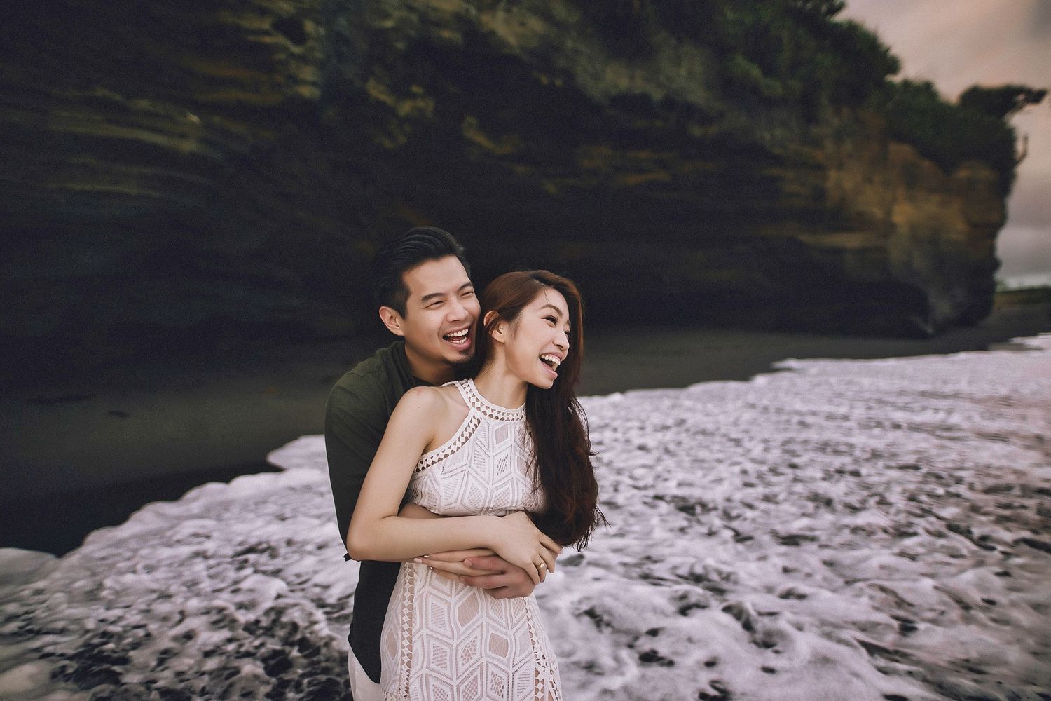 Couple shares intimate moment along rugged coastal cliffs at dusk.