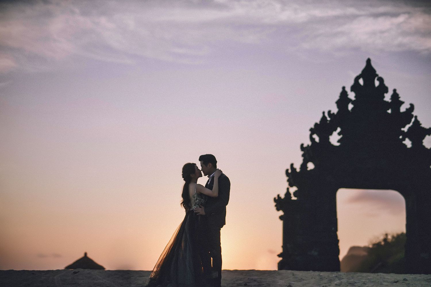 Silhouetted temple architecture and couple at sunset creating dramatic shadows.