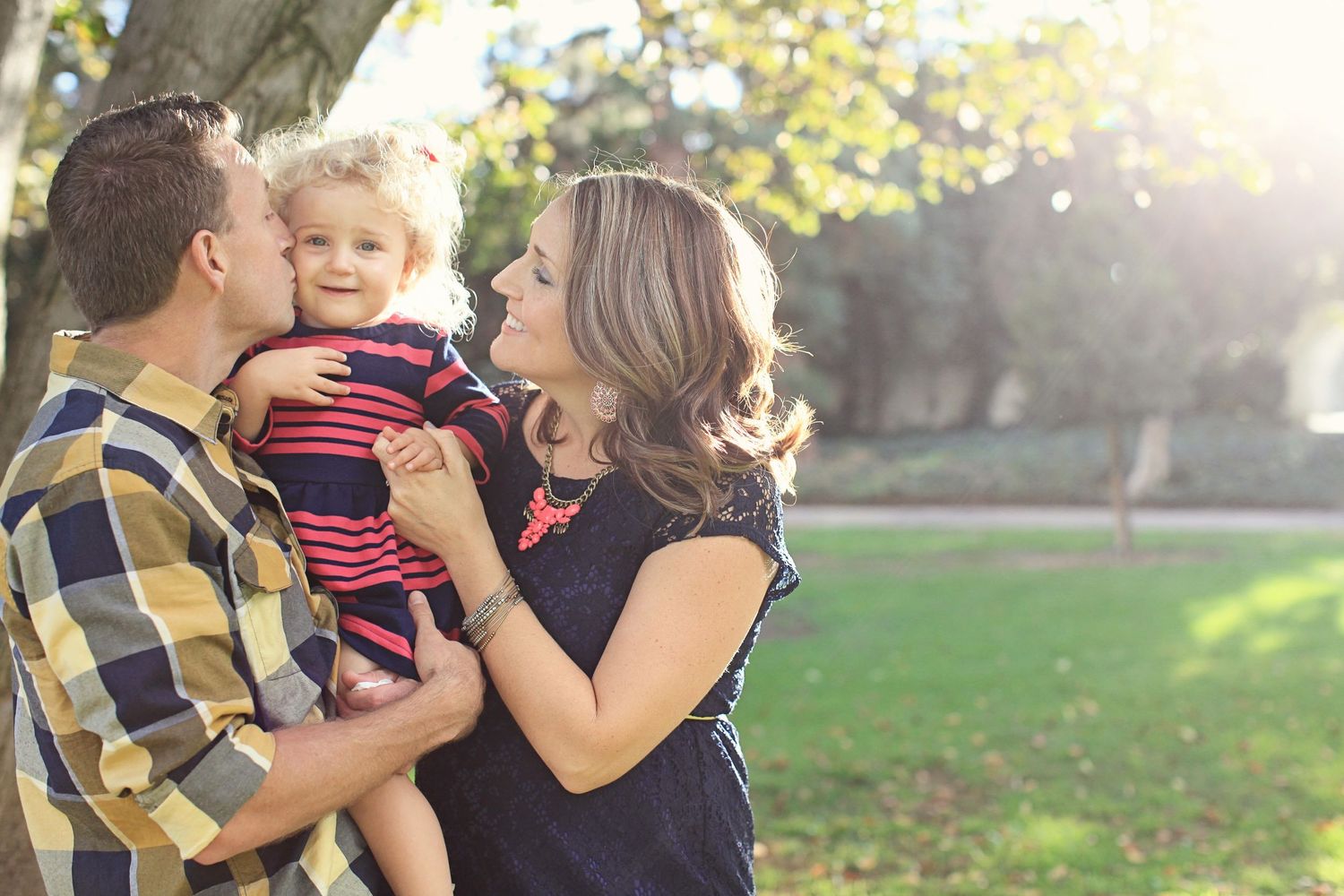 Family sharing a tender moment together outdoors in warm sunlight.