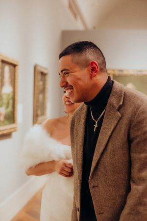 A couple shares a happy moment while looking at artwork in a museum gallery.