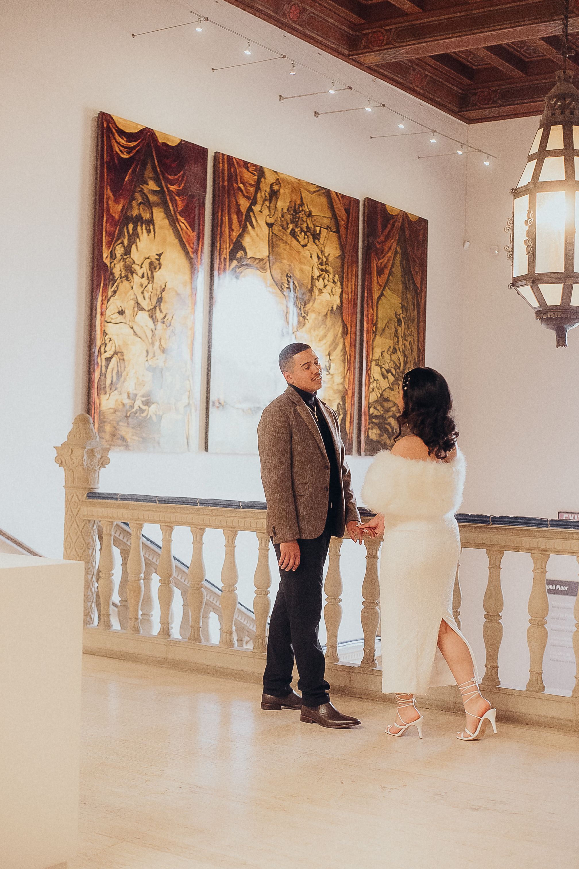 Art gallery interior with decorative columns and large wall murals.