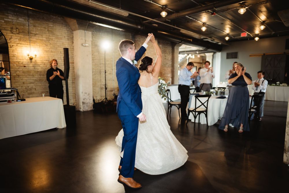 Couple sharing first dance in industrial-style wedding venue with exposed brick walls.