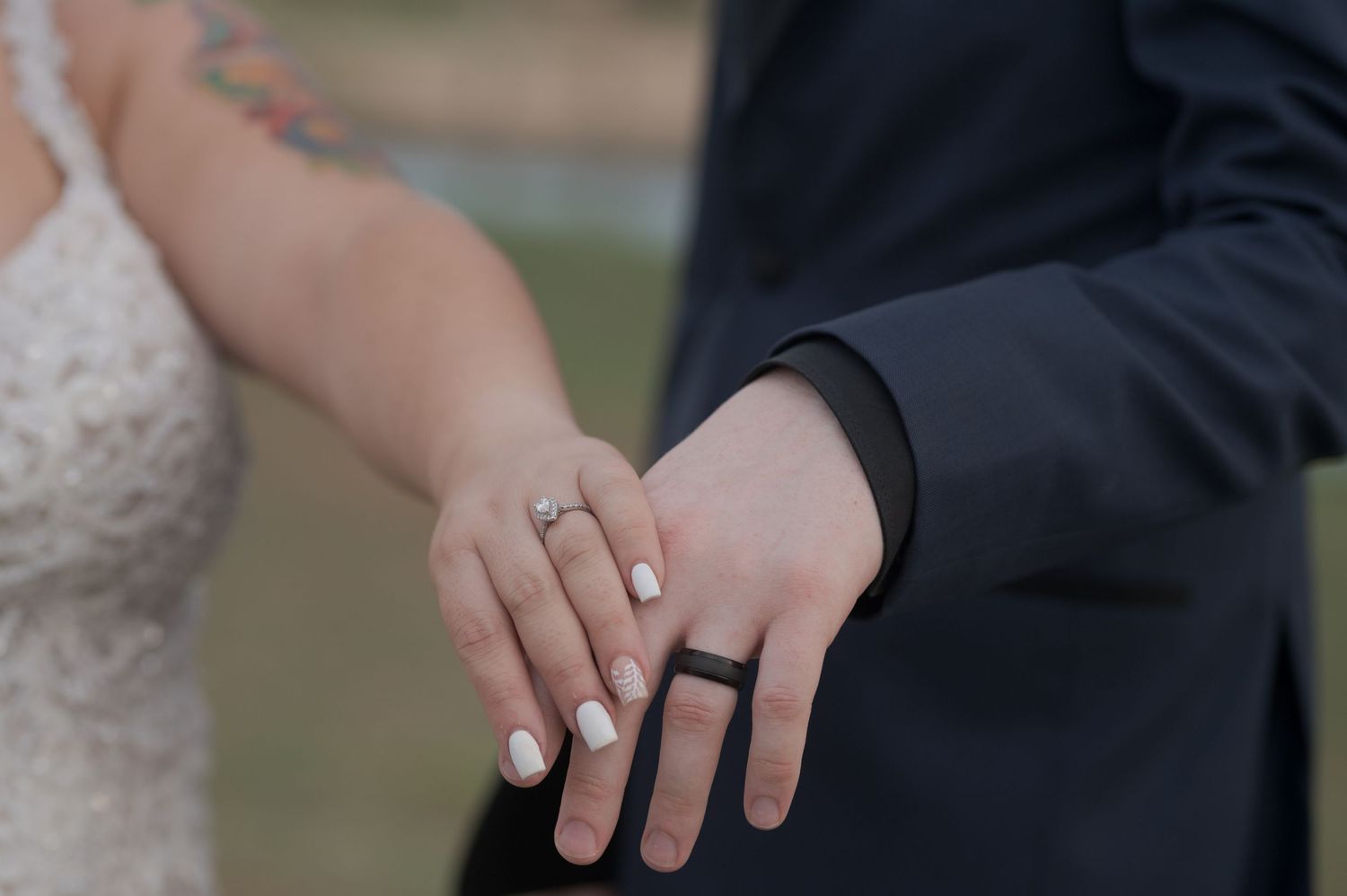 Close-up of newlyweds' hands showing wedding rings against formal attire.