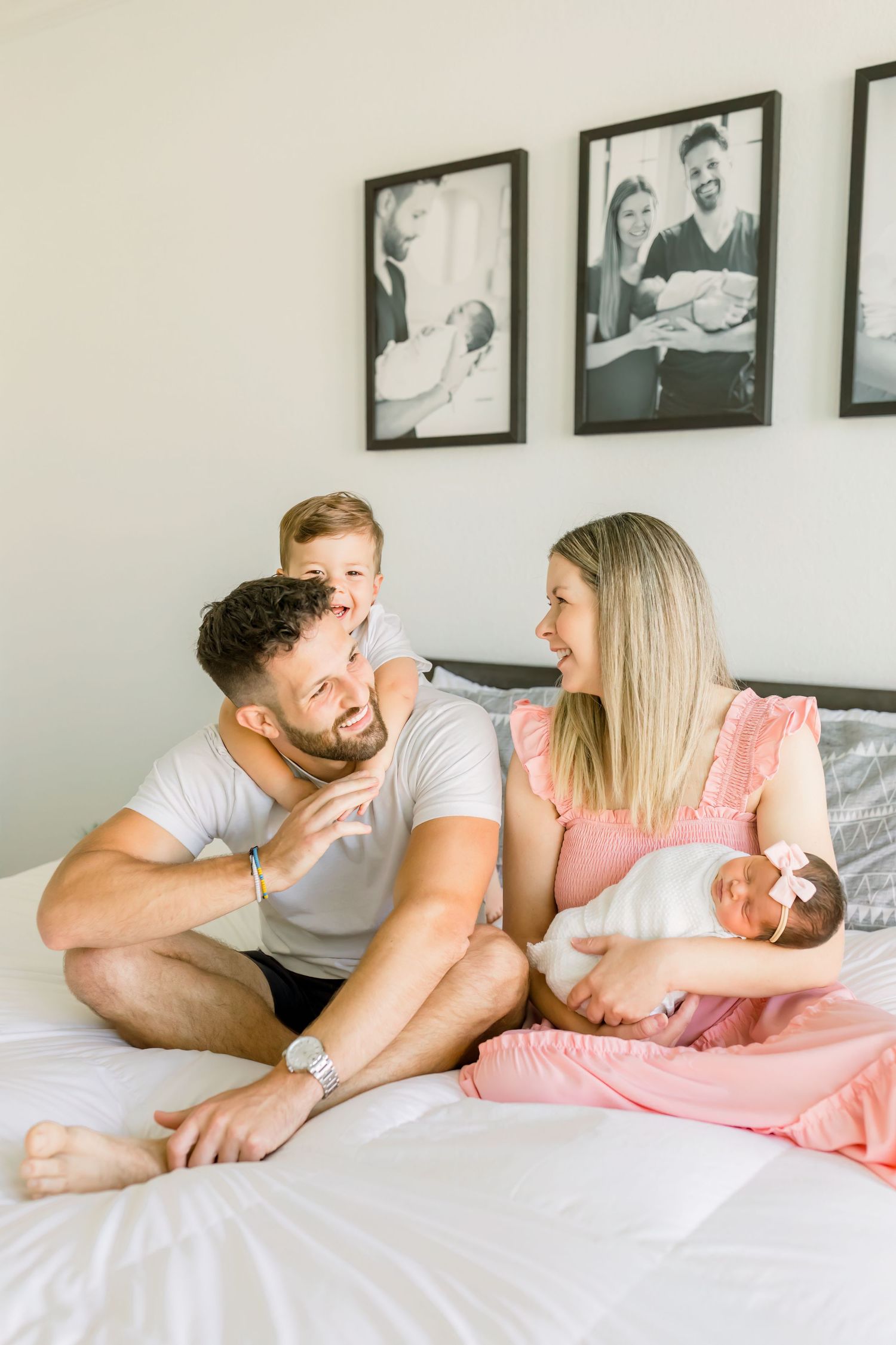 A candid family moment showing laughter and joy while sitting on a white bed.