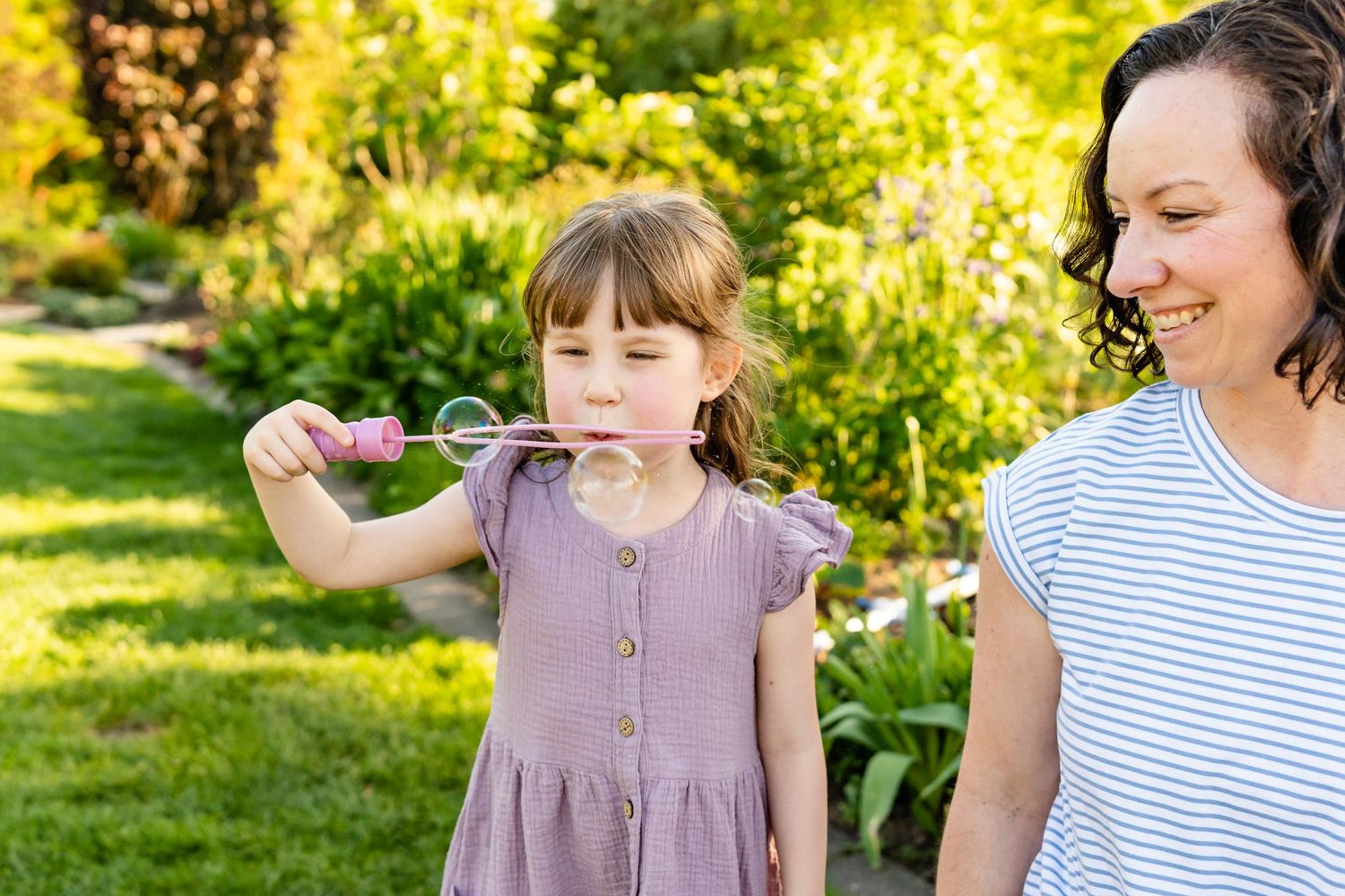 Mother watches daughter blow bubbles at sunset in Bellevue.