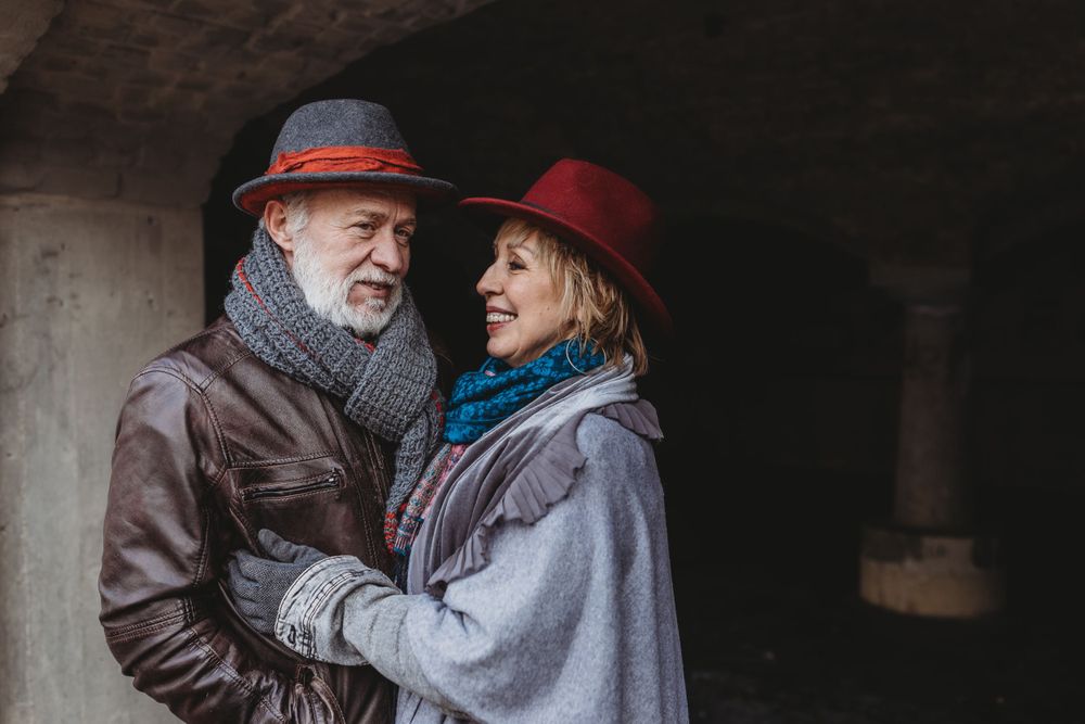 A couple in winter clothing share an intimate moment while standing in an archway.