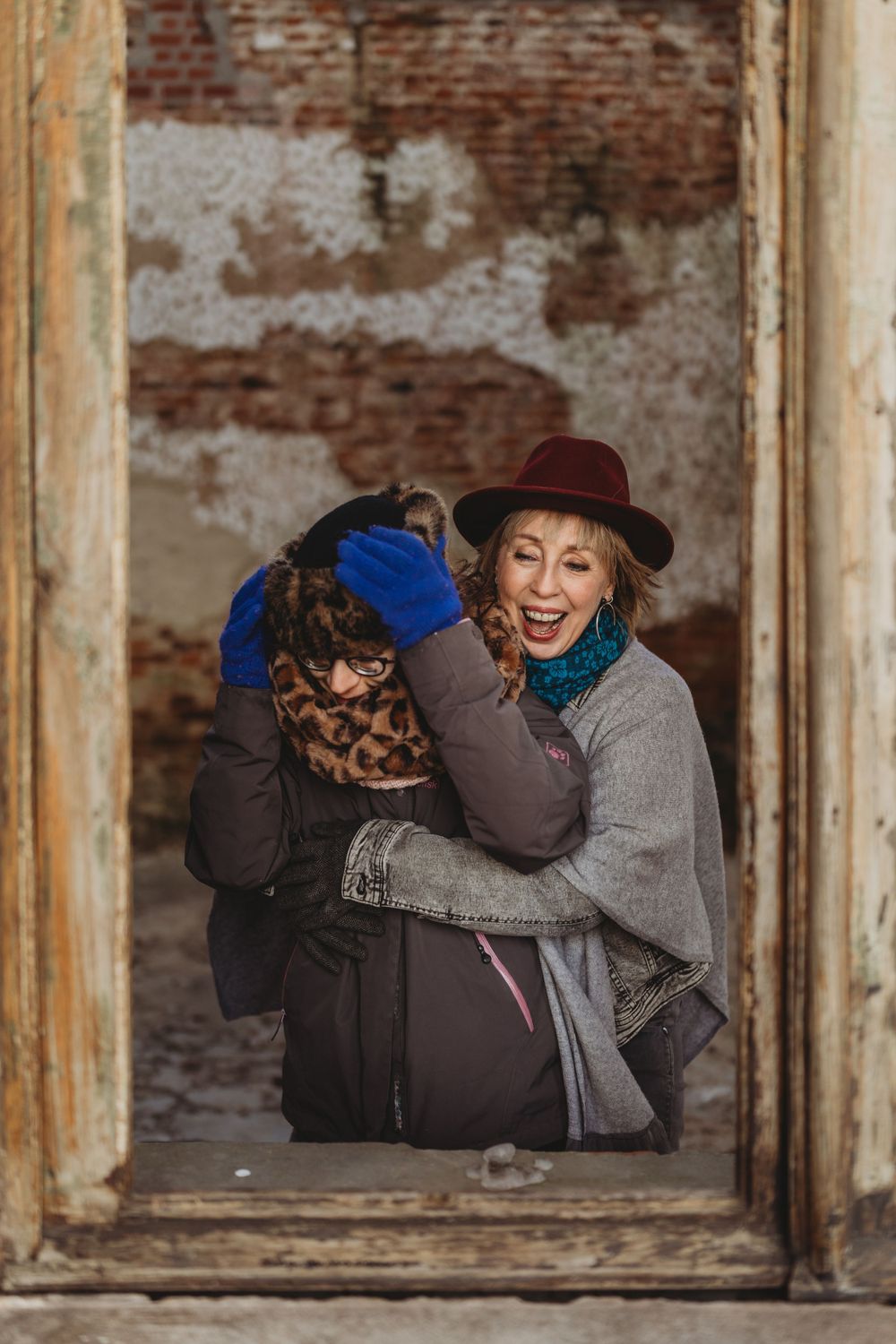 Two people sharing laughter while posing in vintage window frame.