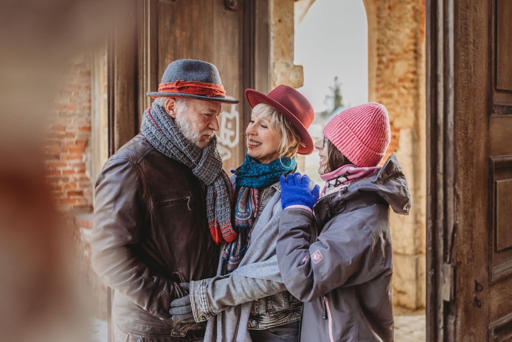 Three people in winter hats and coats sharing an intimate moment in a historic doorway.