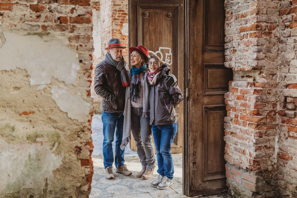 Three people in casual winter clothing posing together in an old brick doorway.