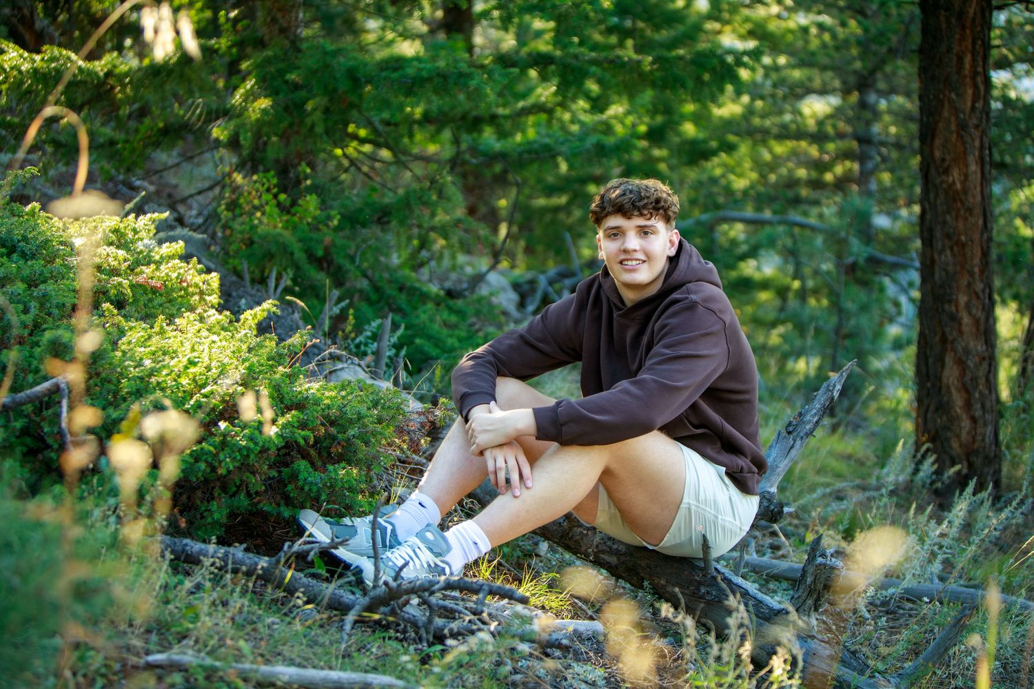 Person relaxing in casual attire on grass surrounded by lush green foliage in outdoor setting.