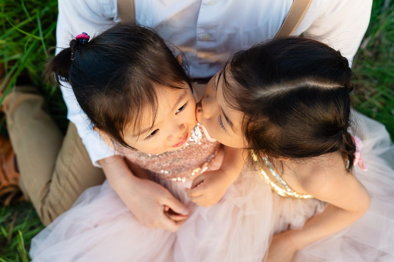 Sisters kissing each other in a lupine field.