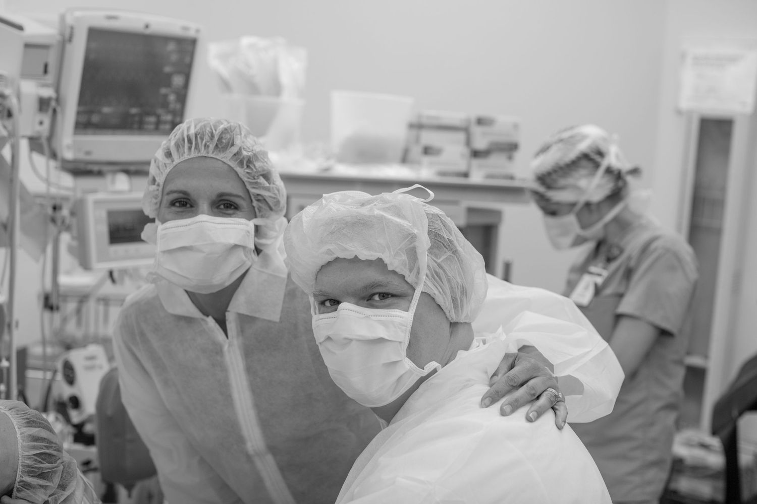Medical professionals in surgical masks and protective gear working together in an operating room.