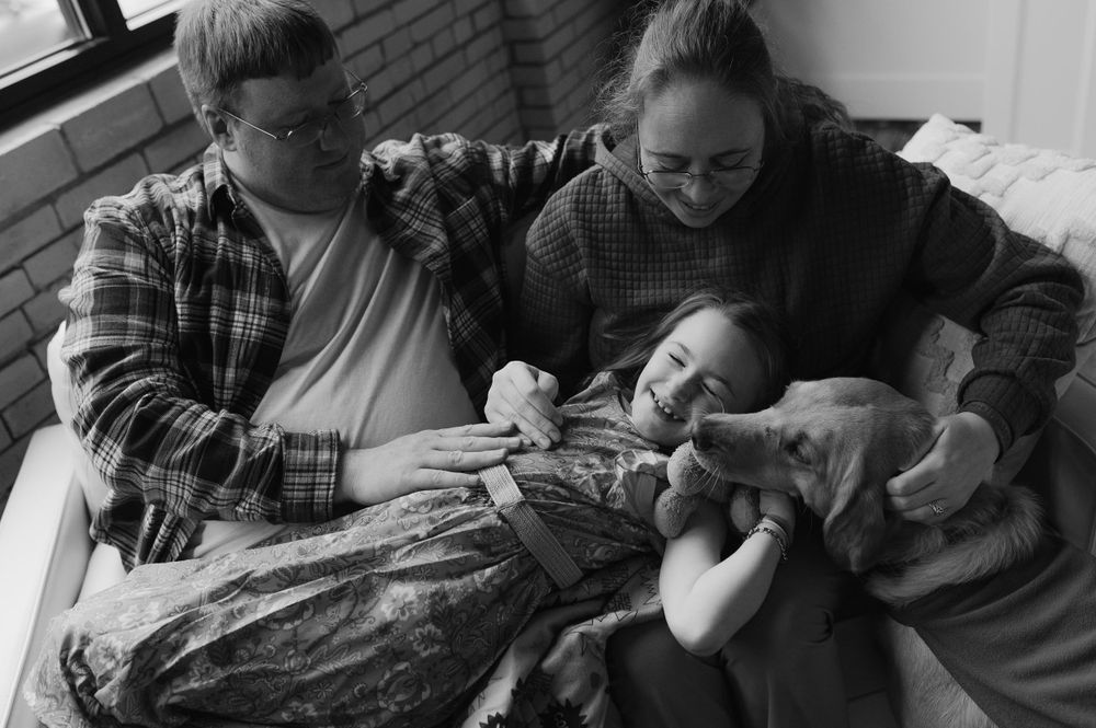 A black and white image of a family with newborn baby resting together.
